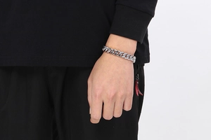 Close-up of a silver stainless steel cuban link bracelet worn on a male wrist