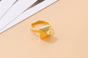 Macro shot showing the geometric pyramid rivet and polished gold finish of the steel ring