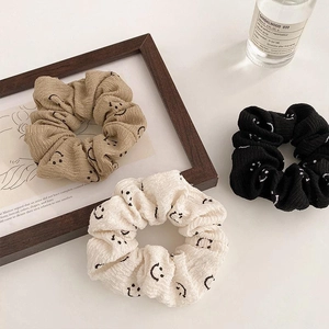 Three-pack minimalist scrunchies with smiley face patterns in khaki, white, and black colors