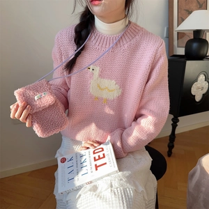 Close-up of pink plush shoulder bag with white duck pattern knit sweater in a cozy setting