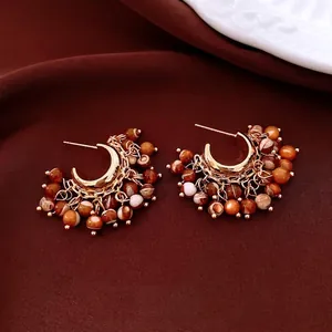 Vintage gold hoop earrings with marble textured beads on a luxury velvet background
