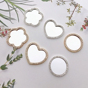 Flat lay of DIY rhinestone compact mirrors in heart, cloud, and round shapes with gold finish