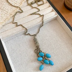 Bohemian retro bronze necklace with turquoise tassels displayed on a beige linen jewelry box