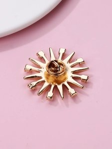 Macro shot of the golden sunburst brooch back with a secure pin clasp and small gems