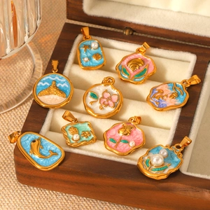 Golden enamel charms with sea creatures and floral pearls in a wooden jewelry box