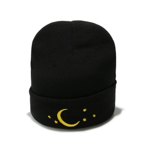 Bonnet en maille noire avec broderie lune et étoiles jaunes sur fond blanc