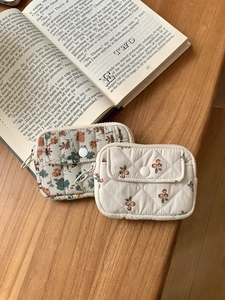 Close-up of quilted fabric card pouches in cherry and floral patterns on wooden table