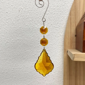 Macro shot of amber crystal suncatcher with maple leaf faceted prism and S-hook