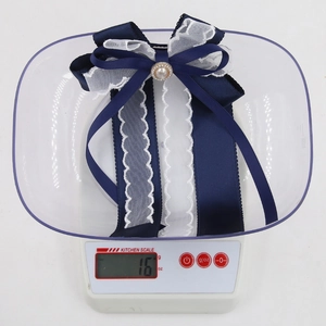 Detailed view of a blue and white ribbon bow with pearl weighing 16 oz on a digital scale