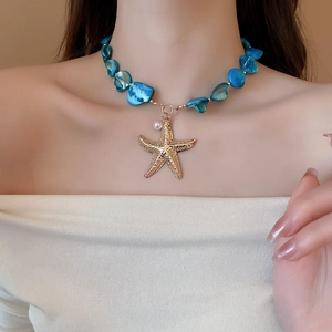 Detail of blue shell and starfish necklace with pearl on model for beach vacation