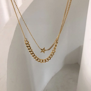 Close-up of golden double-layer chain necklace featuring a hollow star pendant
