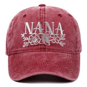 Detailed embroidery of silver NANA letters and floral vines on a washed burgundy baseball cap