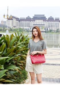 Detail of red quilted diamond pattern shoulder bag with elegant gold twist lock clasp