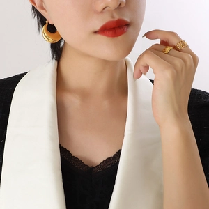 Polished gold U-shaped hoop earrings and textured rings set worn with stylish suit