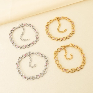 Detail of gold and silver anchor chain bracelets featuring sparkling pink zircon accents