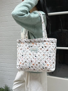 Close-up of quilted floral tote bag showing animal patterns and blue brand label