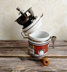 Detailed view of white ceramic manual coffee grinder with espresso patterns on wood table