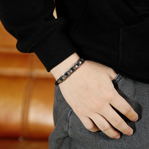 Detail of vintage silver Cuban chain bracelet worn on wrist against leather backdrop