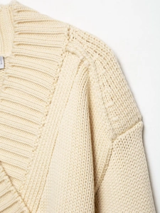 Close-up of cream knit cardigan showing ribbing and premium stitching details