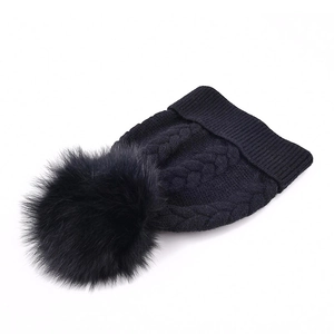Bonnet en maille torsadée noire avec un pompon en fourrure pour une chaleur hivernale