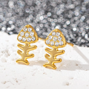 Vue macro de boucles d'oreilles arête de poisson dorées avec cristaux sur pierre blanche
