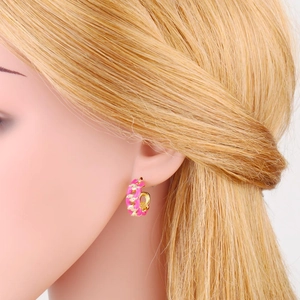 Dettaglio degli orecchini a forma di C dorati con smalto rosa e piccoli zirconi