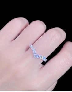 Macro detail of silver V-shaped ring with pavé diamonds on woman's finger