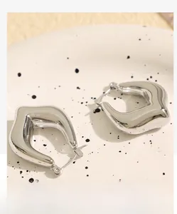 Detailed macro view of silver twisted C-shape metal earrings with liquid metal texture