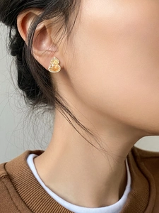 Close-up of champagne zircon gourd stud earring worn by model in warm lighting
