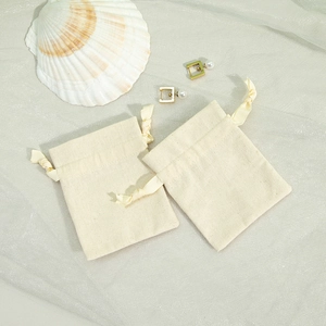 Detailed view of beige cotton linen jewelry pouches with drawstring and shell props