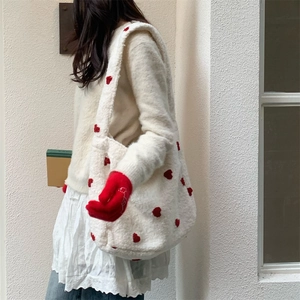 Detail of white plush tote bag with red heart embroidery and soft fleece texture