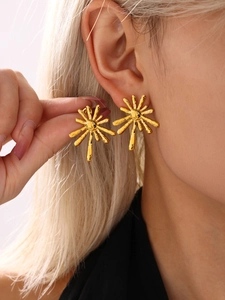 Close-up of 18K gold sunburst stud earring with radiating lines and artistic metallic texture