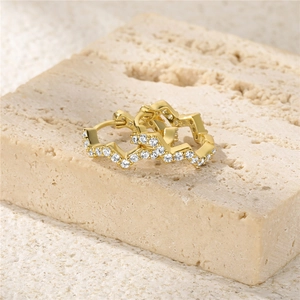 Macro shot of gold-plated wavy hoop earrings with pave-set clear sparkling crystals
