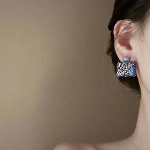 Elegant rectangular blue enamel earrings with gold floral design on female model