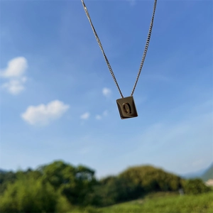 Detailed close-up of a gold-plated titanium necklace with a square 'Q' letter pendant