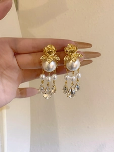 Gros plan sur des boucles d'oreilles rose dorée avec perles et pampilles gouttes d'eau