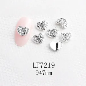 Vue macro de charms d'ongles en cœur 9x7mm avec cristaux micro-pave sur ongles roses