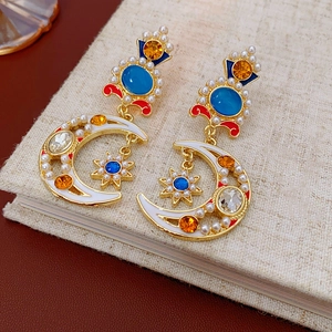 Macro detail of vintage gold earrings with colorful crystals and fringe on a book