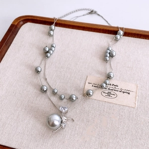 Vue macro d'un collier double couche avec perles grises et pendentif zircon en cœur