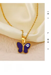 Detailed macro view of gold butterfly pendant with blue enamel evil eye on satin cloth