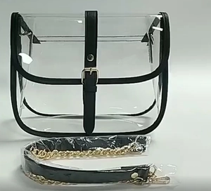 Detail view of transparent PVC saddle bag with black trim and detachable gold chain strap