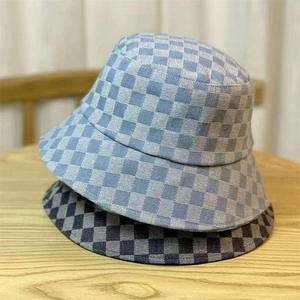 Top view of two checkered denim bucket hats in light blue and grey on a wooden table