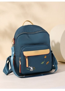 Close-up of cute rabbit embroidery on the front pocket of a navy blue nylon backpack