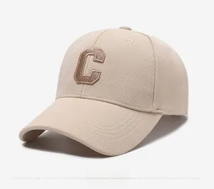 Detailed macro view of the beige baseball cap's mesh texture and 3D brown letter C embroidery
