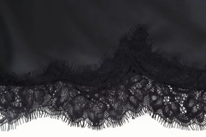 Detailed close-up of high-quality black silk satin fabric with delicate eyelash lace trim