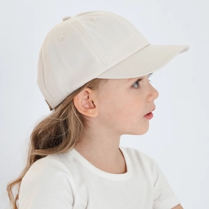 Side profile of a young girl wearing a beige cotton twill baseball cap for kids