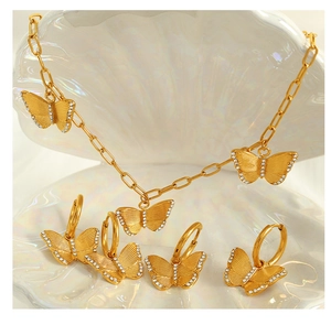 Detailed set of gold butterfly necklaces and earrings with crystals on a shell base