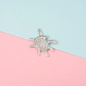 Silver hermit crab charm with intricate metal details on a blue and pink split background