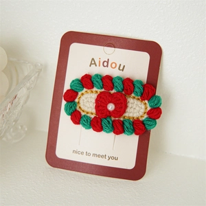 Barrette à cheveux tricotée rouge et verte avec perle blanche sur carte de support