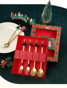 Close-up of golden stainless steel Christmas spoons with festive tree toppers in a gift set